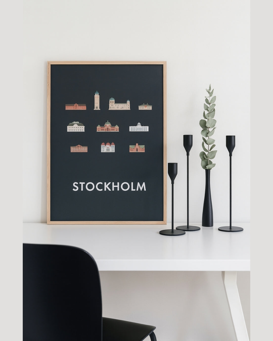 Set om tre mattsvarta ljusstakar på skrivbord framför tavla – modern skandinavisk stil